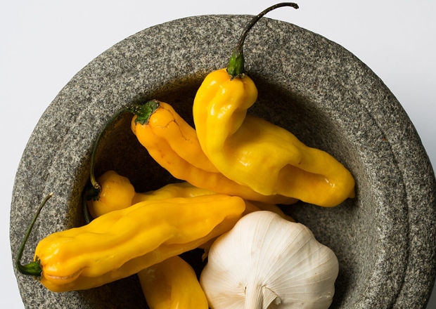 Yellow Madame Jeanette chilli peppers in a granite mortar with a clove of garlic